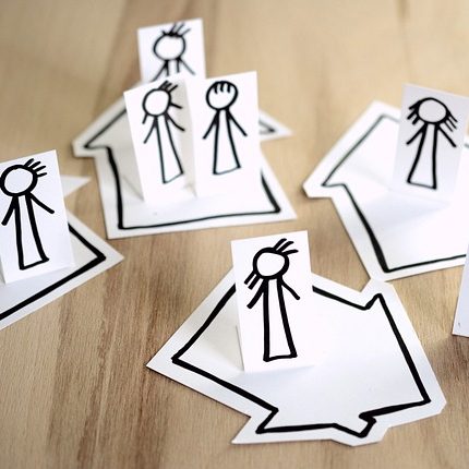 Familienmitglieder stehen auf Papierhäusern